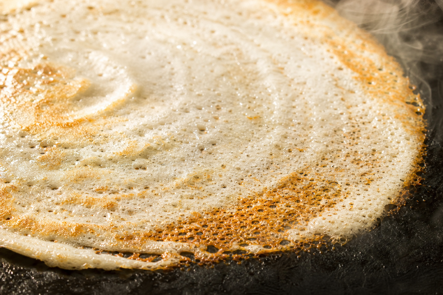 Dosa crêpes fermentées recette en cours de cuisson sur une plaque chaude